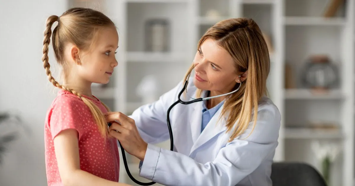 A female doctor using a stethoscope to examine a young girl at a Pediatric Urgent Care center in Braselton, Cumming, and Duluth